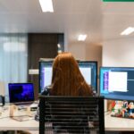 Professionista che lavora con più monitor e strumenti digitali