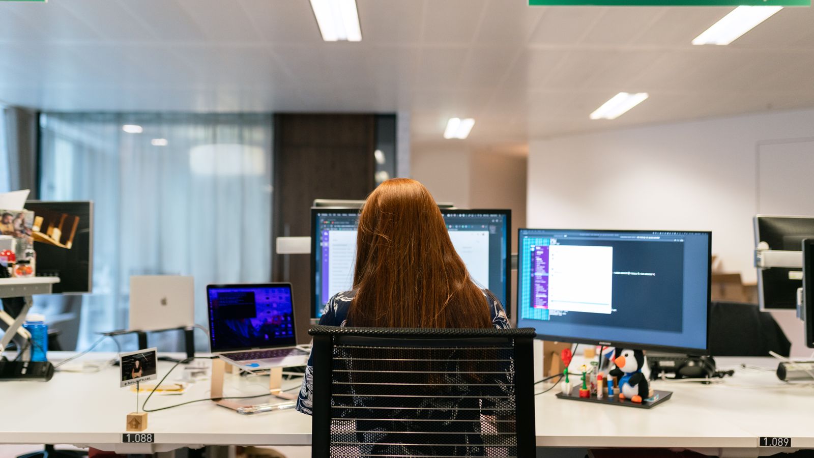 Professionista che lavora con più monitor e strumenti digitali